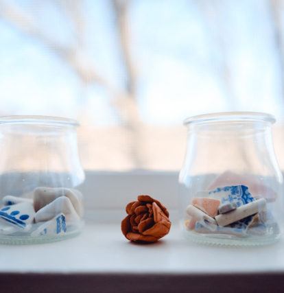 stones in two clear jars with dried rose between them